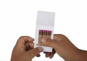 A Child's Hands Holding A Booklet Of Matches